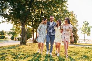 Mann mit drei Frauen, die im Park stehen und sich umarmen foto