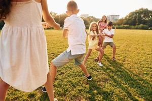 Tauziehen spielen. Eine Gruppe glücklicher Kinder ist tagsüber draußen auf dem Sportplatz foto