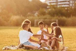 miteinander kommunizieren. Eine Gruppe glücklicher Kinder ist tagsüber draußen auf dem Sportplatz foto