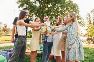 etwas trinken. Eine Gruppe junger Leute feiert tagsüber im Sommer eine Party im Park foto