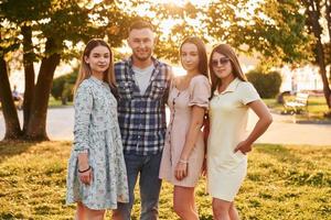 Mann mit drei Frauen, die im Park stehen und sich umarmen foto