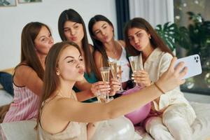 Gläser mit Getränken halten. Gruppe glücklicher Frauen, die auf einem Junggesellinnenabschied sind foto