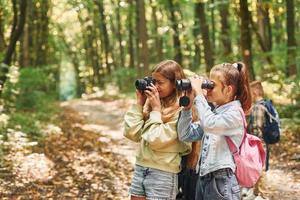 Vorderansicht von Kindern, die im Sommer tagsüber zusammen im grünen Wald sind foto