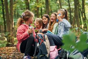 sitzen und sich ausruhen. kinder im grünen wald im sommer tagsüber zusammen foto