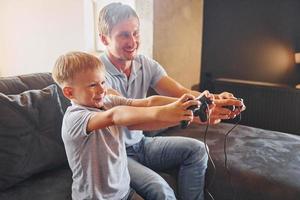 mit Videospiel-Joysticks. Vater und Sohn sind zusammen zu Hause foto