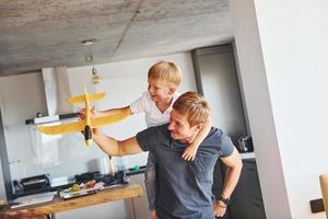 Spielen mit gelbem Spielzeugflugzeug. Vater und Sohn sind zusammen zu Hause foto