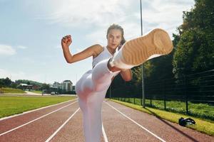 Selbstverteidigungskonzept. Junge Frau in sportlicher Kleidung trainiert im Freien foto