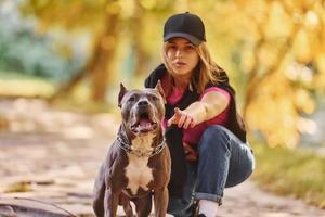 zusammen spielen. Frau in Freizeitkleidung ist mit Pitbull im Freien foto