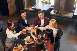 Freizeit. gruppe junger freunde, die zusammen in der bar mit bier sitzen foto