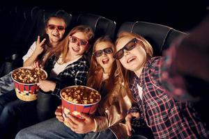 Selfies machen. gruppe von kindern, die im kino sitzen und zusammen filme ansehen foto