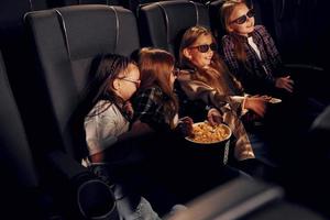 Spaß haben. gruppe von kindern, die im kino sitzen und zusammen filme ansehen foto