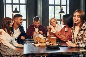 Freude empfinden. gruppe junger freunde, die zusammen in der bar mit bier sitzen foto