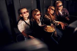 Spaß haben. gruppe von kindern, die im kino sitzen und zusammen filme ansehen foto