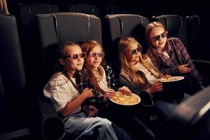 Wochenendspaß. gruppe von kindern, die im kino sitzen und zusammen filme ansehen foto