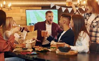 gegen fernsehen. gruppe junger freunde, die zusammen in der bar mit bier sitzen foto