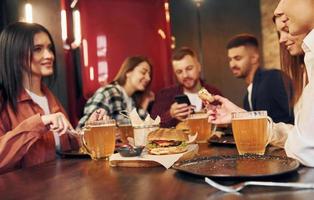 modernes Interieur. gruppe junger freunde, die zusammen in der bar mit bier sitzen foto