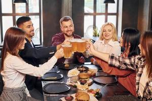 nettes Gespräch. gruppe junger freunde, die zusammen in der bar mit bier sitzen foto