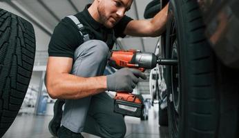 modernes Fahrzeug. Mann in Uniform arbeitet tagsüber im Autosalon foto