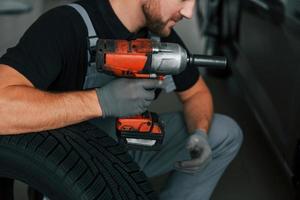 mit Ausrüstung. Mann in Uniform arbeitet tagsüber im Autosalon foto