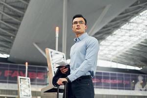 junger männlicher passagier in formeller kleidung ist am flughafen foto