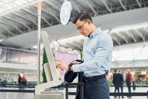 junger männlicher passagier in formeller kleidung ist am flughafen foto