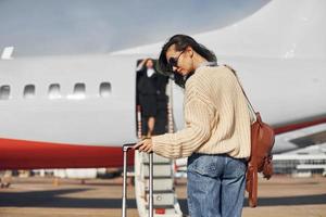 tagsüber. Junge Passagierin in Freizeitkleidung ist draußen in der Nähe des Flugzeugs foto