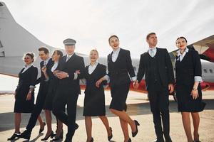 in der nähe von flugzeug. Crew von Flughafenangestellten in formeller Kleidung, die zusammen im Freien stehen foto