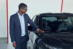 junger afroamerikanischer geschäftsmann im schwarzen anzug ist der autosalon foto