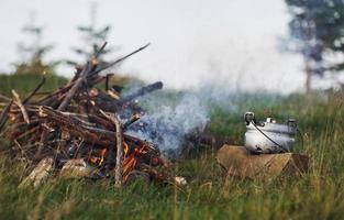 Tagsüber aktives Lagerfeuer auf der Wiese. wolkiges Wetter foto