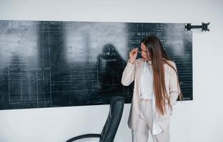 junge intelligente frau mit brille, die nahe tafel steht foto