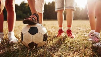 Partikelansicht von Kindern, die an sonnigen Tagen mit Fußball auf dem Feld stehen foto