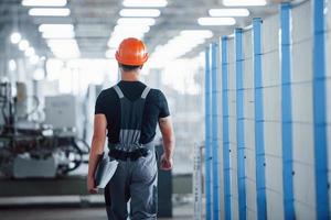 Industriearbeiter drinnen in der Fabrik. junger Techniker mit orangefarbenem Schutzhelm foto