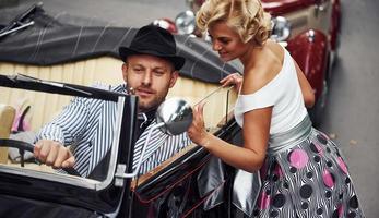 Schönes Paar in altmodischer Kleidung ist in der Stadt mit Retro-Auto foto