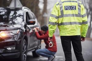 polizist in grüner uniform erwischt autodiebstahl auf der straße foto