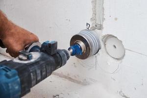 Baumeister mit Hammerbohrer Perforator bohrt Loch in eine Wand foto