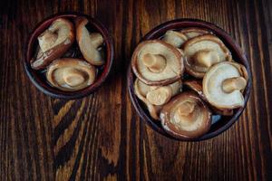 eingelegte Pilze in Tonbechern stehen auf einem Holztisch. gesalzene Pilze. rustikales essen. foto