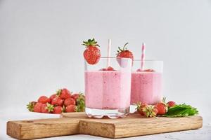 Erdbeermilchshake im Glas mit Stroh und frischen Beeren foto