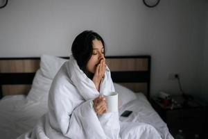 Frau in eine Decke gehüllt und hält einen Becher foto