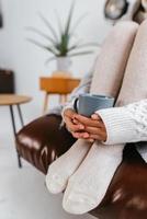 abgeschnittene Aufnahme einer sitzenden Frau, die einen Becher zu Füßen hält foto