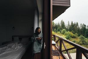 Frau sitzt auf der Fensterbank und schaut auf die Berge foto