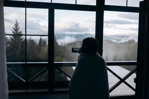 Frau fotografiert von einem Hotelzimmer aus eine Berglandschaft foto