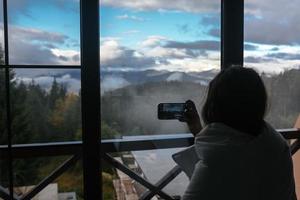 Frau fotografiert von einem Hotelzimmer aus eine Berglandschaft foto