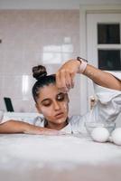 Müde junge Frau gießt Mehl auf den Küchentisch foto