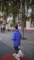 Rückansicht einer erwachsenen Frau, die draußen auf einer Straße läuft foto