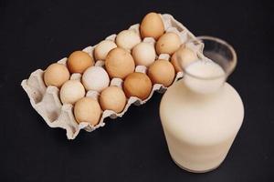 Draufsicht auf Eier im Behälter und Glas frische Milch auf dunkler Oberfläche foto