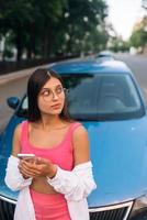 Frau mit Handy in der Nähe des Autos auf der Straße foto