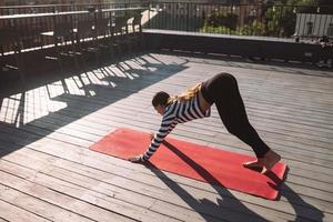 Frau, die am frühen Morgen Yoga-Übungen auf dem Hausdach macht foto