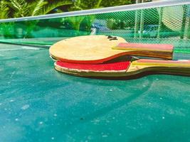 Tischtennis. kleine rote schläger liegen auf einem tisch aus grünem stoff. Doppelspiel mit einem kleinen Ball. aktive Freizeitgestaltung, unterhaltsamer Zeitvertreib in einem Hotel in einem Resort foto