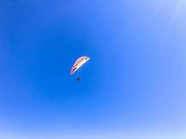 Gleitschirmfliegen in einem heißen Land. Fallschirmspringen vom Berg, aktive Erholung. Ein Mann in einem Schutzanzug fliegt in einem Ballon foto