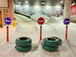 Schneeraum. Straße im Schnee mit Reifen und Verkehrszeichen. auf dem Schnee ein Hügel, auf dem die Leute reiten können. Unterhaltung im Schneeraum. extreme Rutschen foto